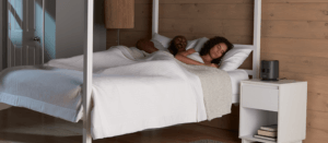 a couple sleeping soundly in a bed next to a Honeywell bedroom fan