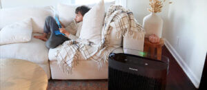 a child playing with a tablet on a couch next to a air purifier for dust and allergens